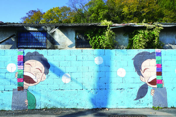 담벼락에 어린아이 두명이 활짝 웃고있는 그림이 그려져 있는 벽화