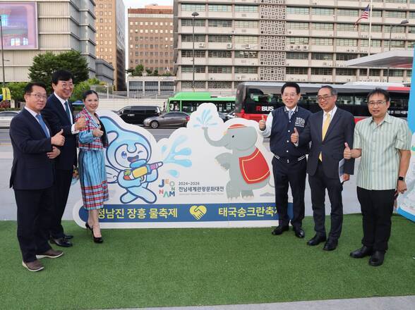 정남진 장흥 물축제 태국송크랑 축제 입간판을 뒤로하고 따봉포즈를 취하며 사진을 찍는 관계자들(크게보기)