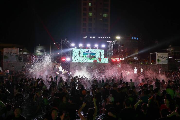 많은사람들이 풀파티를 즐기면서 물을 뿌리고 즐거워 하고 있다.