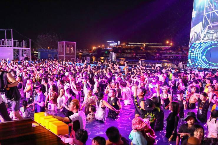 EDM풀파티 현장의 풀장 안에서 많은 사람들이 공연을 보고 있다.
