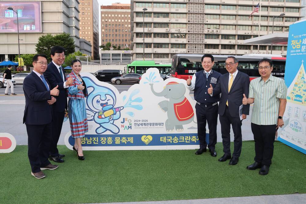 정남진 장흥 물축제 태국송크랑 축제 입간판을 뒤로하고 따봉포즈를 취하며 사진을 찍는 관계자들